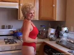 Very sexy grandma turns half-naked in the kitchen, maybe a neighbor will call.