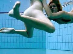 Two naked girls caress underwater.